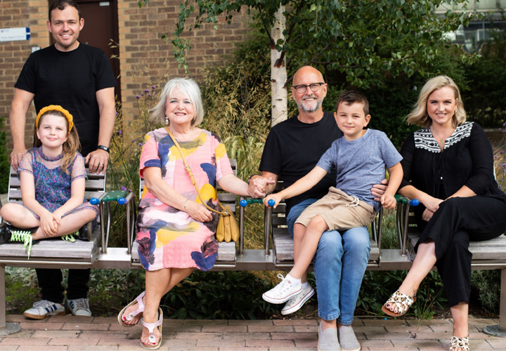 A bench with people of all ages sat upon it.